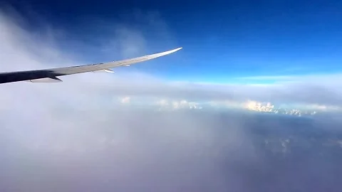 Plane travelling through the clouds with beautiful sun rays shining across Stock Footage 141095364