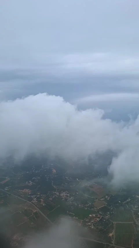 From a plane window during descent, flying through thick white clouds reveal Stock Footage 335177235