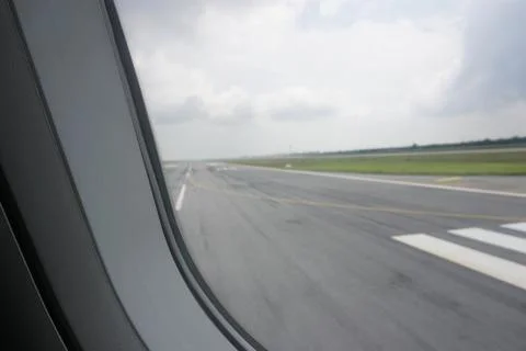 Plane window view during take off with airplane runaway tarmac Stock Photos