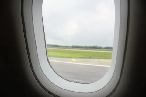 Plane window view during take off with airplane runaway tarmac Stock Photos