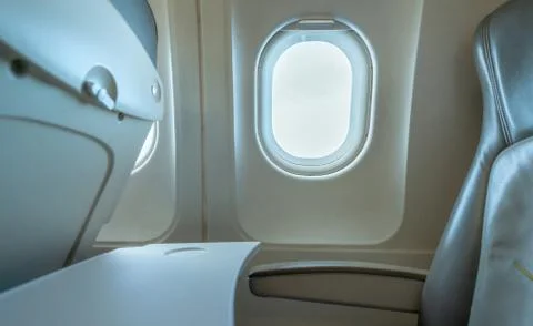 Plane window with white sunlight. Empty plastic airplane tray table at seat b Foto stock