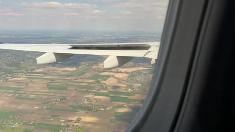 Plane wing above cultivated fields with view of scattered houses Stock Footage 310677528