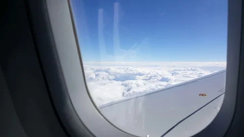 Plane wing, flight above clouds, window frame, sunlight flare, blue sky Video stock 74667023