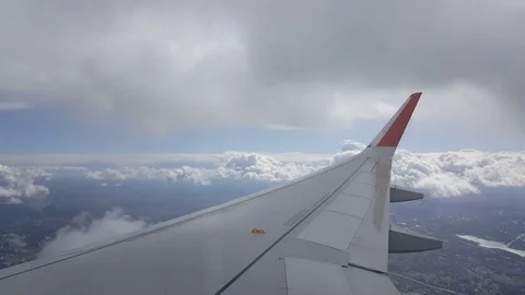 Plane wing at flight through clouds, visible roads, houses, distant ground Stockbeeldmateriaal 74668121