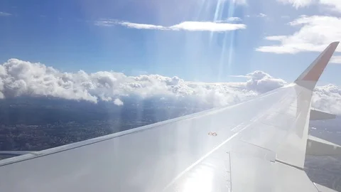 Plane wing, flight through clouds, far away roads, buildings, sunlight flare Vídeos de archivo 74668147