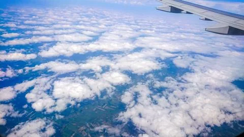 Plane wing glides above fluffy white clouds Stock Photos