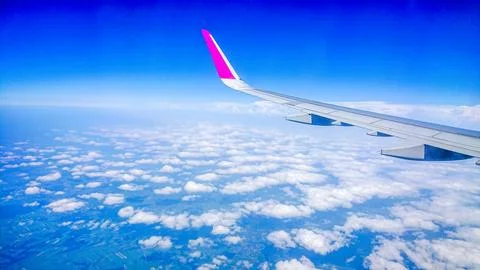 Plane wing glides above fluffy white clouds Stock Photos