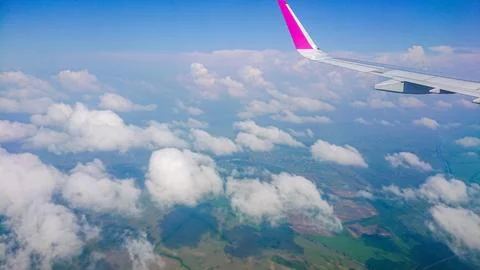 Plane wing glides above fluffy white clouds Stock Photos