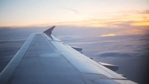 Plane wing at golden sunset with orange clouds beneath and on the horizon 스톡 동영상 119336777