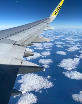 A Plane Wing High Above the Clouds With a Yellow Tip That Says Hello Stock Photos