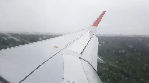 Plane wing at landing, rain on window, forest, buildings in distance, Moscow Stockbeeldmateriaal 74978864