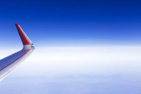 Plane wing with red wingtip on background of blue sky Stock Photos