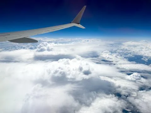 Plane wing soars above fluffy white clouds Stock Photos