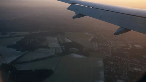 Plane wing through window with sunrise sky and city below Stock-Footage 87257335