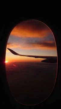 Plane wing through the window in a sunset Stock Photos