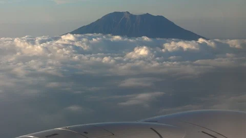 Plane wing with top of volcano coming out of clouds Stock Footage 112482736