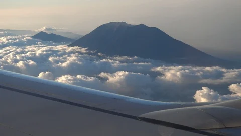 Plane wing with top of volcano coming out of clouds 스톡 동영상 112482926
