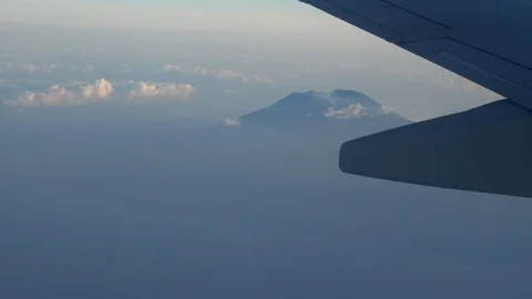 Plane wing with volcano surrounded by fog and island coast below Stock-Footage 112483023