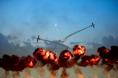 Planes doing tricks during high explosive flames rise up Stock Photos