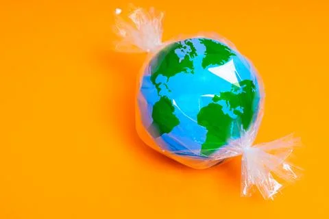 Planet Candy: Globe Wrapped in Plastic on Yellow 스톡 사진