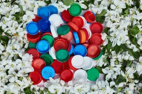 Planet pollution concept. plastic caps on a background of flowers Fotos Stock