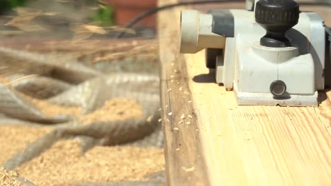Planing an old board with an electric plane in sunlight. Refresh the wood plank Stock Footage 142361059