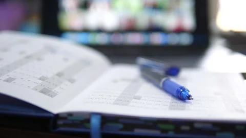 Planner Notebook and Pen with Blurred Online Meeting Screen Video stock 309978893