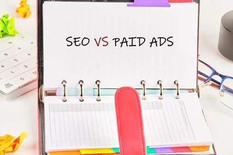 A planner is open with notes comparing seo and paid ads. Colorful tabs are vi Stock Photos