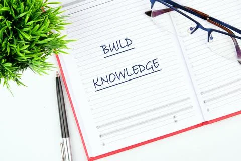 A planner open to a page featuring the words 'build knowledge.' Glasses and.. Stock Photos