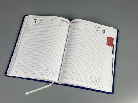 Planner open on a table showing dates and notes for organizing tasks Stock Photos
