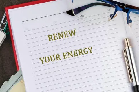 A planner opened to a page featuring the phrase renew your energy. A pen and  Stock Photos