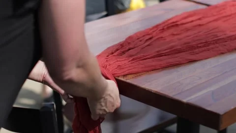 Planner tying a knot at the end of a table runner for an outdoor dinner Stock Footage 317602351