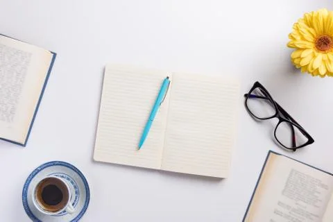 Planning concept. Open notebook and books, cup of coffee, flower, on white ba Stock Photos