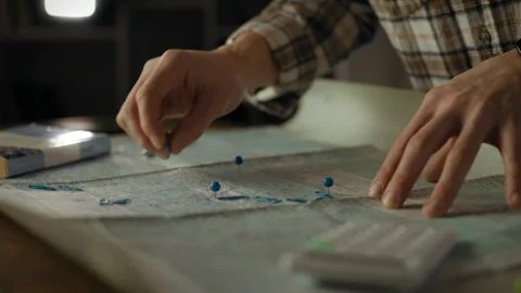 Planning a detailed route with maps and markers during a quiet evening indoo Stock Footage 299037725
