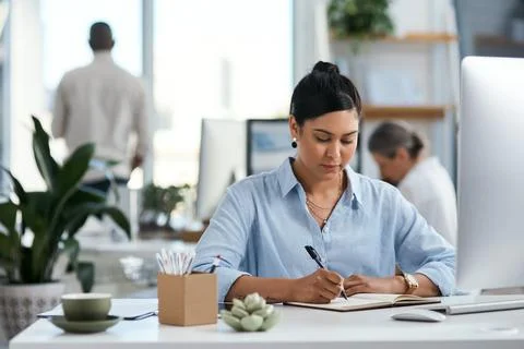 Planning her tasks ahead. a young businesswoman writing notes in an office. Stock Photos