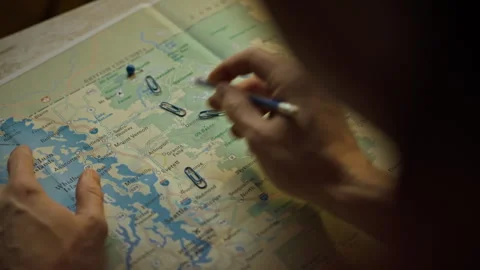 Planning a trip with a map and stationery in a cozy indoor setting Stock Footage 297709599