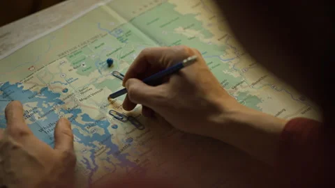 Planning a trip using a detailed map and markers in a cozy setting Stock Footage 303650748