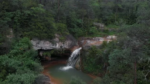 Plano aereo drone de cascada espectacular con un arroyo y una cueva en medio Stock Footage 134642032
