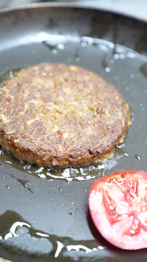 Plant-based vegan burger cooking in pan with tomato slice 库存影片 340406645