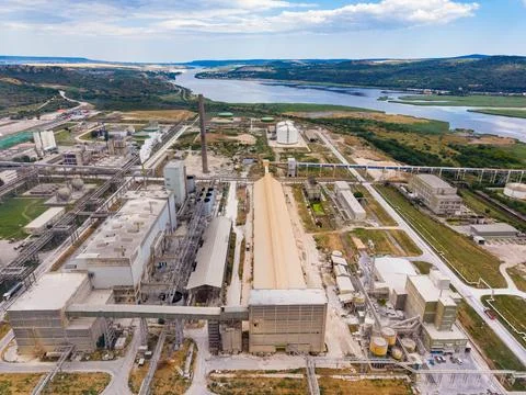 Plant complex located by a river with machinery and storage areas visible d.. Stock Photos