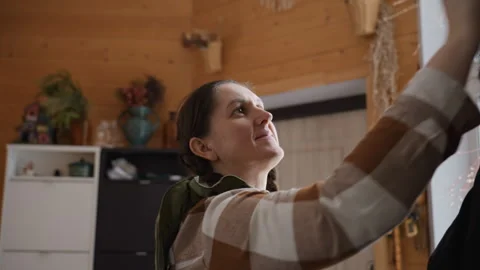 Plant Lover Grabs Hat from Hanger and Places It on Head in Cozy Room Vídeo Stock 309038606