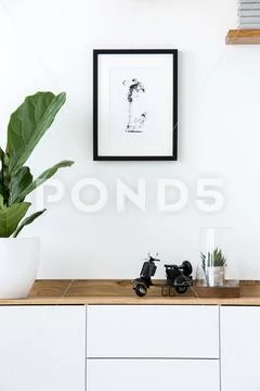Plant on wooden white cupboard in simple living room interior with poster. Re Stock Photos