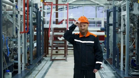 A plant worker straightens an orange work helmet, a process equipment operator Stock Footage 167690779