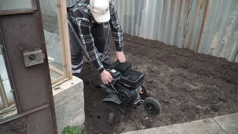 Planting potatoes under the walk-behind tractor. Man with motor-block in the gar Stock Footage 96388022