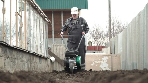 Planting potatoes under the walk-behind tractor. Man with motor-block in the gar Stock-Footage 96389366