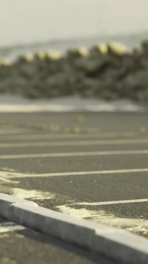 Plants grow through cracks in an empty parking lot near the ocean Stock-Footage 334724685
