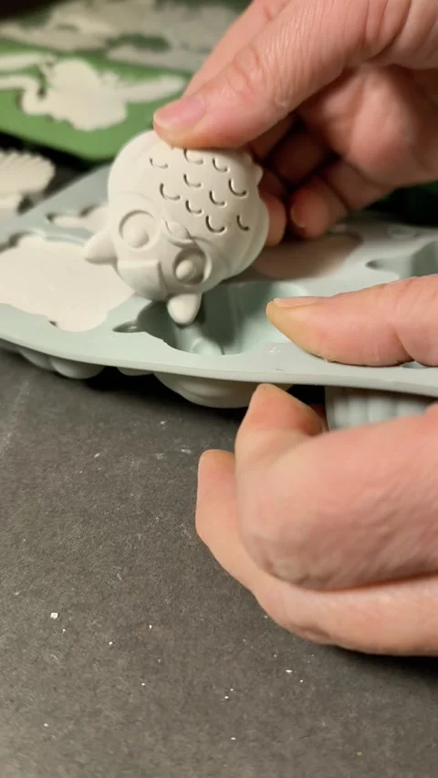 Plaster figure coming out of silicone mold, hands lifting crafted item, Stock Footage 338244054