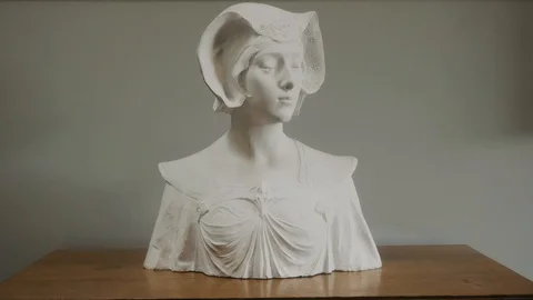 A plaster figure stands on a table against a white wall Stock Footage 119954377