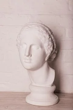 Plaster head of the statue against the background of a white brick wall Stock Photos