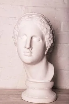 Plaster head of the statue against the background of a white brick wall Stock Photos